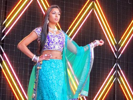a woman in teal presenting her outfit on stage