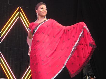 a woman in red presenting her outfit on stage